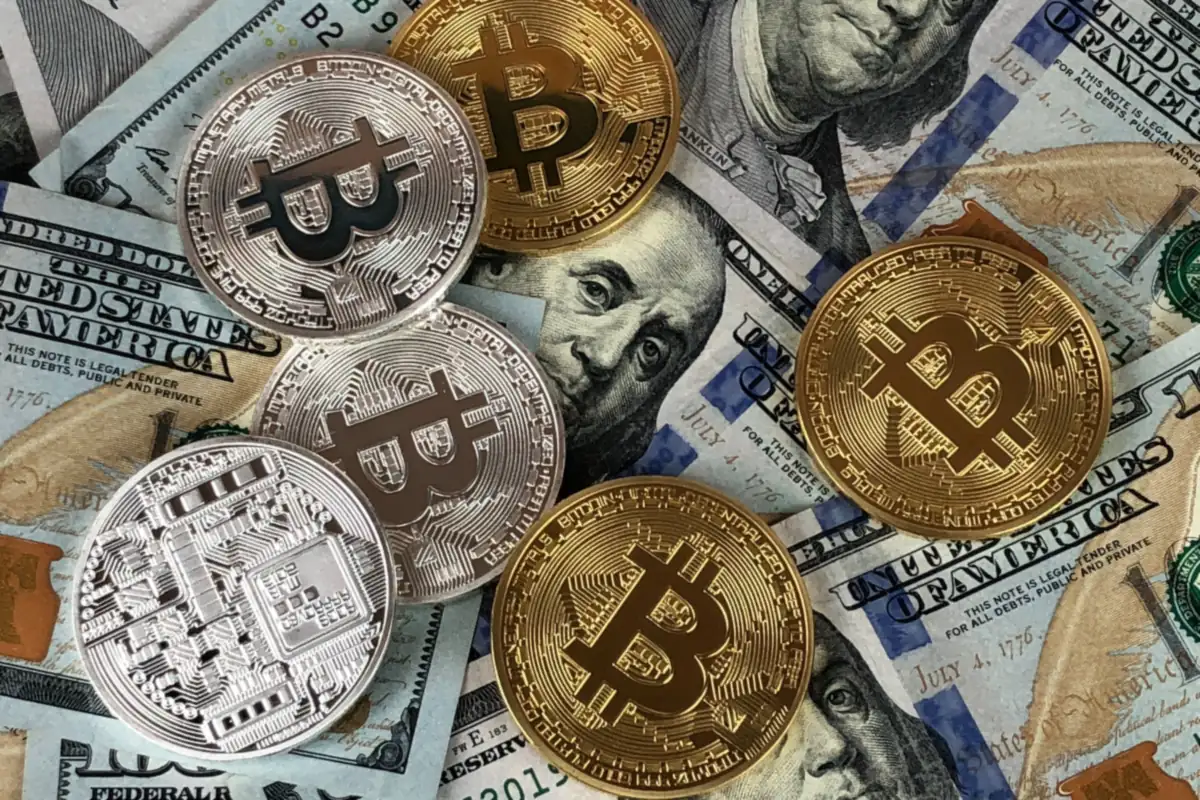 Metal bitcoin coins on top of dollar bills
